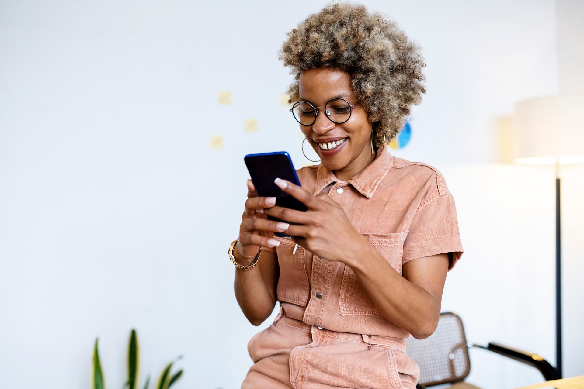 Smiling female entrepreneur using her smartphone at home office.