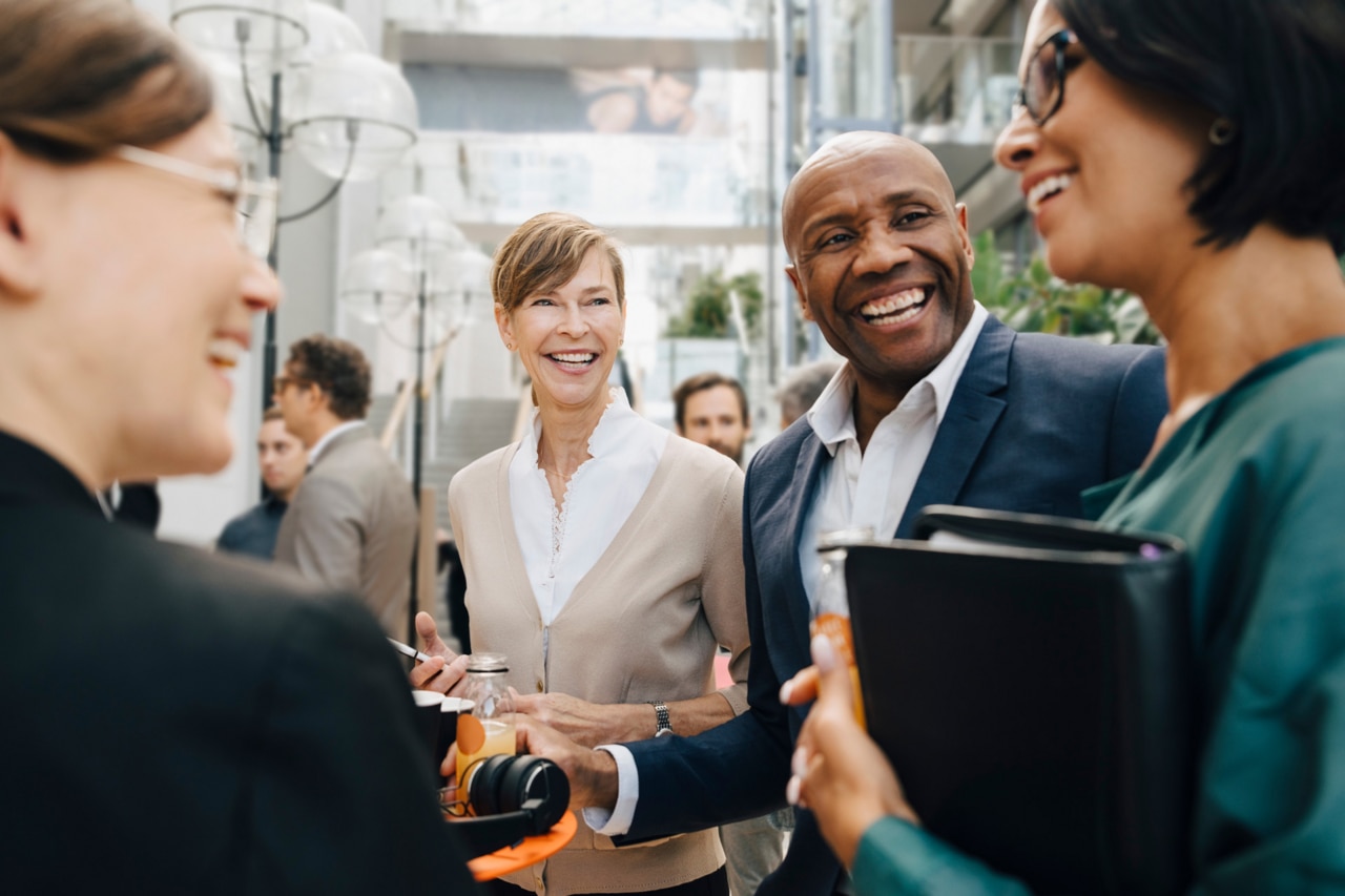 Smiling male and female business people talking while standing in the office.
